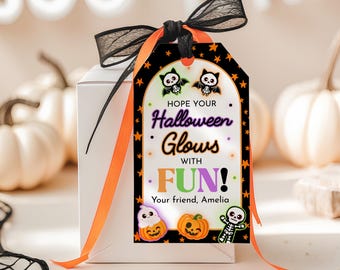 May include: A white gift box with a Halloween-themed tag. The tag features bats, pumpkins, and a skeleton graphic, with the text "Hope your Halloween Glows with FUN!" and "Your friend, Amelia". The tag is tied with black and orange ribbons.