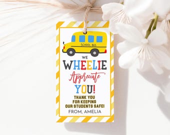 以下が含まれることがあります： 黄色と白の感謝タグ。漫画のスクールバスと「We Wheelie Appreciate You! Thank you for keeping our students safe! From, Amelia.」というテキストが書かれています。