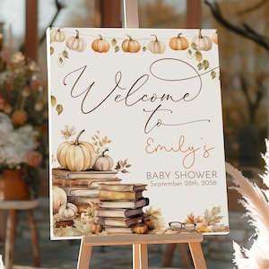 May include: A welcome sign for Emily's baby shower, featuring a fall theme. The sign displays the words "Welcome to Emily's Baby Shower" with pumpkins, books, and leaves. The date of the baby shower is September 28th, 2058.