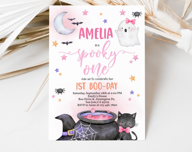 May include: A pink and purple Halloween-themed first birthday party invitation for Amelia. The invitation features a ghost, a witch's cauldron, a black cat, and stars. The text reads "Amelia is a spooky one. Join us to celebrate her 1st Boo-Day. Saturday, September 28th at 2:00 PM. Emily's House. Boo Drive & Donington Dr. San Jose, CA 95129. RSVP to Anne at 123-456-7890."
