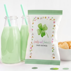 May include: A white chip bag with a green shamrock design and gold glitter accents. The bag has the text "Emily and James's Baby Shower" printed on it.