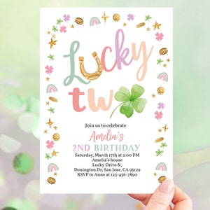 May include: A white invitation card with a green shamrock, gold coins, and rainbows. The text reads "Lucky Two" and "Join us to celebrate Amelia's 2nd Birthday".
