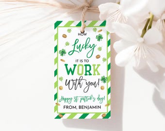 May include: A St. Patrick's Day gift tag with a green and white striped border. The tag features the text "How Lucky It Is To Work With You!" with shamrocks and gold coins. The tag also says "Happy St. Patrick's Day!" and "From, Benjamin."