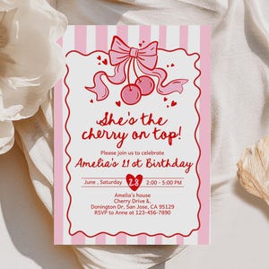 Puede incluir: Una tarjeta de invitación rosa y blanca con el texto "She's the cherry on top!" y detalles para el 21 cumpleaños de Amelia. El diseño incluye una ilustración de cereza, un lazo y acentos de corazón. La tarjeta está sobre un fondo blanco.
