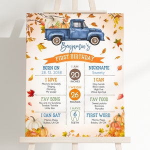 Puede incluir: Un gráfico de hitos del primer cumpleaños para imprimir con una camioneta azul con calabazas en la caja. El gráfico incluye detalles como el nombre del niño, la fecha de nacimiento, la altura, el peso, la canción favorita, la primera palabra y otros hitos. El fondo es de estilo acuarela con hojas de otoño y calabazas.