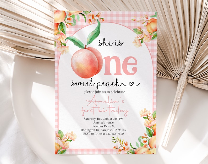 Op de afbeelding: Een roze en witte gingham achtergrond met een perzikillustratie en de tekst "she is one sweet peach" en "please join us to celebrate Amelia's first birthday". De uitnodiging bevat details voor het feest, inclusief de datum, tijd, locatie en RSVP-informatie.