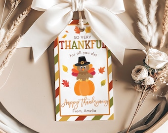 Può includere: Bigliettino regalo del Ringraziamento con un fiocco di nastro bianco. Il bigliettino presenta un tacchino dei cartoni animati con un cappello da pellegrino su una zucca arancione, con il testo "So Very Thankful" e "Happy Thanksgiving".