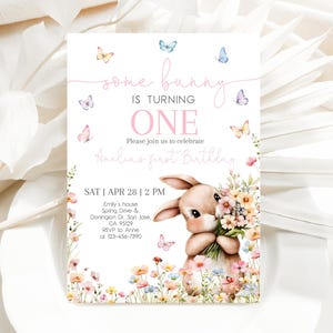 May include: A pink and white invitation card with a bunny holding flowers. The text on the card reads "some bunny is turning one. Please join us to celebrate Amelia's first birthday. Sat | Apr 28 | 2 PM. Emily's house, Spring Drive & Donington Dr. San Jose, CA 95129. RSVP to Anne at 123-456-7890."
