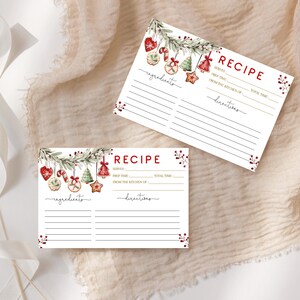 May include: Two white recipe cards with a Christmas theme. Each card has a red "RECIPE" header and lines for ingredients and directions. The cards are decorated with watercolor illustrations of Christmas ornaments and greenery.