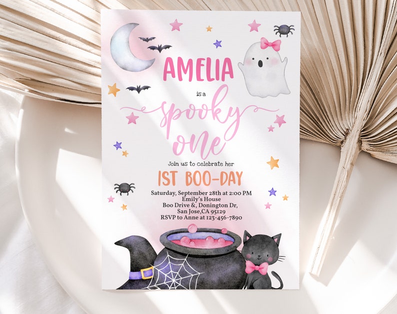 May include: A pink and purple Halloween-themed first birthday party invitation with a ghost, a cauldron, a black cat, and stars. The invitation says "Amelia is a spooky one" and includes the date, time, and location of the party.