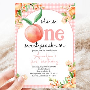 Op de afbeelding: Roze en witte gingham achtergrond met een perzikillustratie en de tekst "she is one sweet peach" en een hartje. De tekst "please join us to celebrate Amelia's first birthday" staat onder de perzik. De uitnodiging bevat de datum, tijd, locatie en RSVP-informatie.