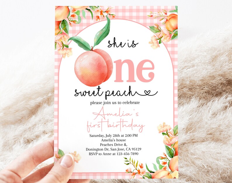 Op de afbeelding: Roze en witte gingham achtergrond met een perzikillustratie en de tekst "she is one sweet peach" en een hartje. De tekst "please join us to celebrate Amelia's first birthday" staat onder de perzik. De uitnodiging bevat de datum, tijd, locatie en RSVP-informatie.