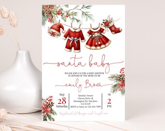 Könnte beinhalten: Eine Weihnachts-Babyparty-Einladung mit einem roten und weißen Santa-Anzug und einem Kleid, die an einer Wäscheleine hängen. Der Text lautet "santa baby" und "Bitte schließen Sie sich uns zu einer Babyparty zu Ehren der werdenden Mutter Emily Brown an". Das Datum ist der 28. September um 14:00 Uhr.