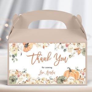 Può includere: Una scatola portaconfetti marrone con un'etichetta bianca con un motivo floreale con zucche e il testo "Thank You for coming Love, Amelia".