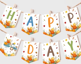 May include: A white banner with the word "HAPPY" in colorful letters, decorated with fall leaves and pumpkins. The banner is strung with clothespins and has a tractor with a load of pumpkins on the "D" flag.