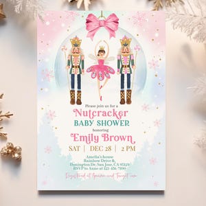 May include: A pink and blue baby shower invitation with a Nutcracker theme. The invitation features a Nutcracker soldier, a ballerina, and a snowflake design. The text on the invitation reads "Please join us for a Nutcracker Baby Shower honoring Emily Brown, SAT | DEC 28 | 2 PM".