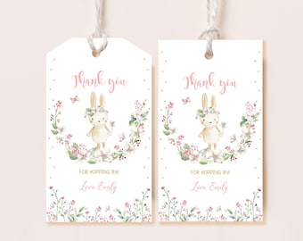 May include: Two white thank you tags with a pink bunny rabbit wearing a flower crown and holding a flower. The bunny is surrounded by a wreath of pink and green flowers. The text "Thank you" is written in pink letters. The text "For hopping by! Love, Emily" is written in pink letters.