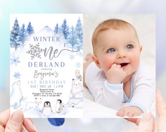 May include: A blue and white winter wonderland themed first birthday invitation with a photo of a baby boy. The invitation features a silver glitter snowflake, a white mountain, and a blue and white penguin. The text on the invitation reads "Winter One Derland celebrating Benjamin's 1st Birthday Sat Dec 28 2 PM Benjamin's house Winter Drive & Donington Dr. San Jose, CA 95129 RSVP to Anne at 123-456-7890".