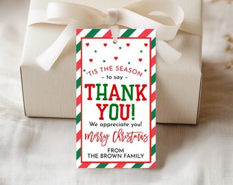 Może przedstawiać: Prostokątna etykieta prezentowa z czerwono-zieloną obwódką w paski i słowami "'Tis the Season - to say - THANK YOU!" w kolorze czerwonym i zielonym. Etykieta zawiera również napisy "Merry Christmas" i "FROM THE BROWN FAMILY". Etykieta jest przymocowana do białego pudełka prezentowego z białą wstążką.