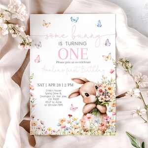 May include: A pink and white invitation card with a bunny holding flowers. The text on the card reads "some bunny is turning one" and "Please join us to celebrate Anelia's first birthday". The date and time of the party are listed as "SAT | APR 28 | 2 PM".