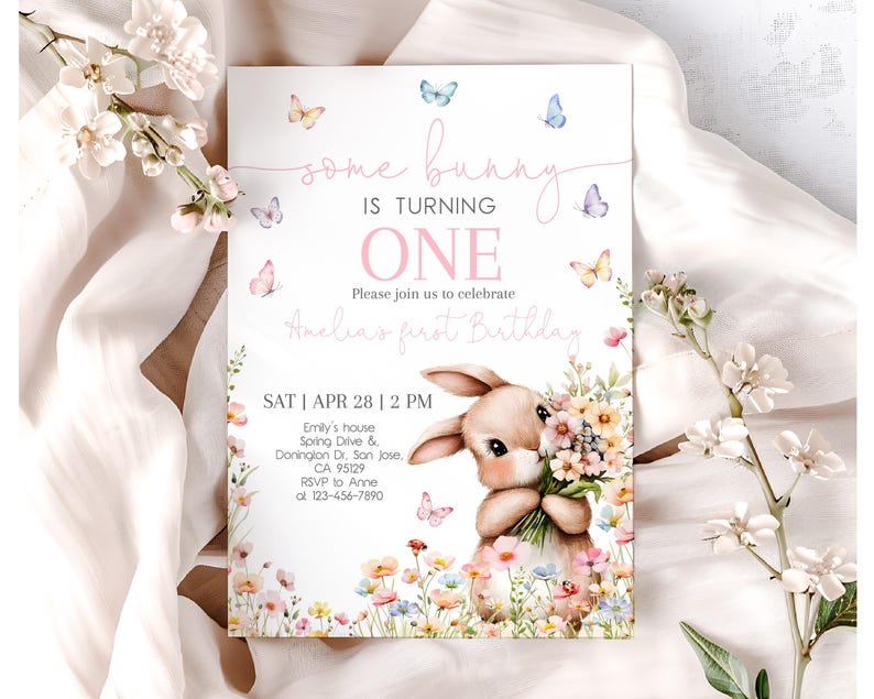 May include: A pink and white invitation card with a bunny holding flowers. The text on the card reads "some bunny is turning one" and "Please join us to celebrate Anelia's first birthday". The date and time of the party are listed as "SAT | APR 28 | 2 PM".