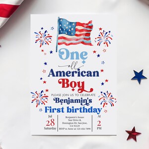 Op de afbeelding: Een witte uitnodigingskaart met een aquarel Amerikaanse vlag en de tekst "One all American Boy". De uitnodiging is voor Benjamin's eerste verjaardag, met de datum 28 juli en de tijd 14:00 uur.