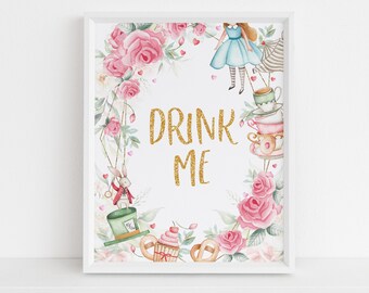 May include: A white framed print with a watercolor illustration of a floral wreath with a gold glitter text that says "Drink Me". The wreath includes a teacup, a rabbit, a cupcake, and a girl in a blue dress.