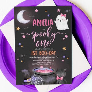 May include: A black and white invitation with a pink and purple ghost, a black cat, and a cauldron. The text reads "Amelia is a spooky one. Join us to celebrate her 1st Boo-Day. Saturday, September 28th at 2:00 PM. Emily's House. Boo Drive & Donington Dr, San Jose, CA 95129. RSVP to Anne at 123-456-7890."