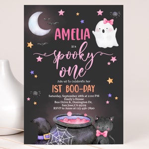 May include: A black and white invitation with a pink and purple design for a first birthday party. The invitation says "Amelia is a spooky one" and includes a ghost, a cauldron, a black cat, and stars. The party is on September 28th at 2:00 PM at Emily's House. The address is Boo Drive & Donington Dr, San Jose, CA 95129. RSVP to Anne at 123-456-7890.