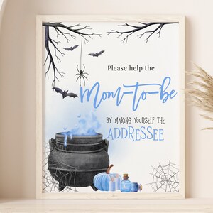 May include: A blue and white Halloween baby shower sign with a cauldron, bats, and a spider. The sign says "Please help the mom-to-be by making yourself the addressee."
