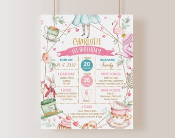 May include: A pink and blue Alice in Wonderland themed first birthday milestone chart. The chart includes details like the child's name, birthdate, weight, height, favourite songs, foods, and things they can do. The chart features illustrations of a flamingo, teacups, a rabbit, and a hat.