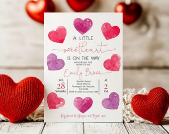 May include: A pink and white baby shower invitation with a watercolor heart design. The invitation reads "A Little Sweetheart is on the Way" and includes the date, time, and location of the event. The invitation is decorated with hearts and the text "Registered at Amazon and Target.com".
