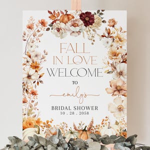 Puede incluir: Un cartel blanco con un borde floral de otoño y el texto "Fall in Love Welcome to Emily's Bridal Shower 10.28.2058".