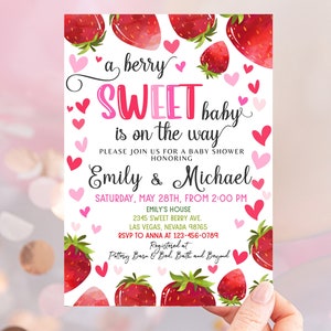 May include: A pink and white baby shower invitation with a watercolor strawberry design. The text reads "a berry sweet baby is on the way" and includes the names "Emily & Michael".