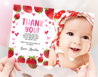 May include: A pink and white thank you card with a strawberry theme. The card features a photo of a baby girl with a strawberry-patterned headband. The text on the card reads "Thank You! I enjoyed the cake and the presents too. But my favorite part was seeing you. Thank you for coming to my party! Love. Amelia."
