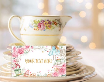 May include: A white tea party place card with a watercolor design of Alice in Wonderland characters, flowers, and teacups. The text "YOUR TEXT HERE" is printed in gold glitter.