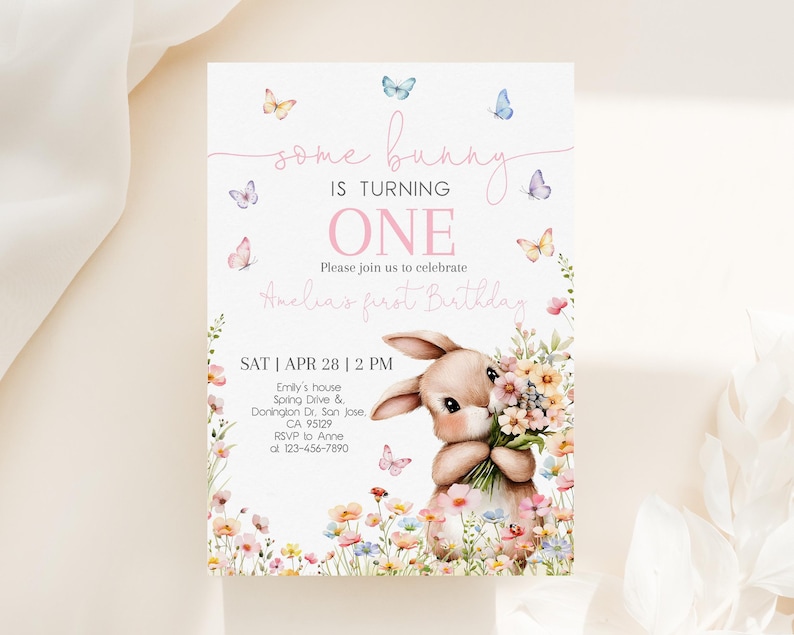 May include: A pink and white invitation card with a bunny rabbit holding flowers. The card says "some bunny is turning one" and "Amelia's first birthday". The invitation includes the date, time, and location of the party.