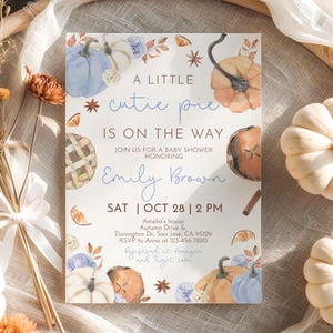 Puede incluir: Una invitaci&oacute;n a un baby shower con calabazas de acuarela, hojas y el texto "A LITTLE cutie pie IS ON THE WAY" en escritura azul. La invitaci&oacute;n incluye el nombre "Emily Brown" y los detalles del evento.