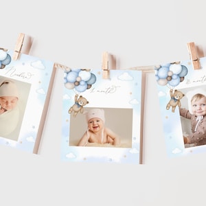 May include: A set of three blue and white baby milestone cards with a teddy bear holding balloons. The cards feature a photo frame with the text "newborn", "1 month", and "2 months".