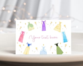 May include: A printable card with a white background and a pink, green, yellow, blue, and purple watercolor illustration of princess dresses. The text "Your text here" is written in pink cursive.