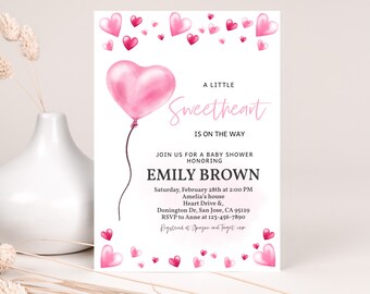 Puede incluir: Una invitación de baby shower rosa y blanca con un globo en forma de corazón rosa y el texto "A Little Sweetheart is on the Way". La invitación incluye el nombre "Emily Brown" y los detalles de la ducha, incluida la fecha, la hora, la ubicación y la información de RSVP.