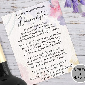 K&ouml;nnte beinhalten: Eine Gru&szlig;karte mit dem Text "TO MY WONDERFUL Daughter" und einer herzlichen Botschaft. Die Karte ist 9,5 cm breit und 12,1 cm hoch, mit floralen Akzenten und einem Perlenrand. Eine Weinflasche ist teilweise sichtbar.