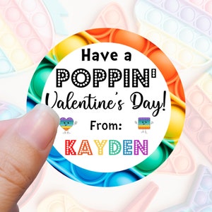 May include: A round Valentine's Day sticker with a rainbow pop-it design. The sticker says "Have a Poppin' Valentine's Day!" and "From: KAYDEN".