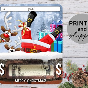 May include: A Christmas gift card with a cartoon image of Santa Claus falling on his back with reindeer peeking out from behind the snow. The card has a dollar sign on each side and the text "Merry Christmas!" at the bottom.