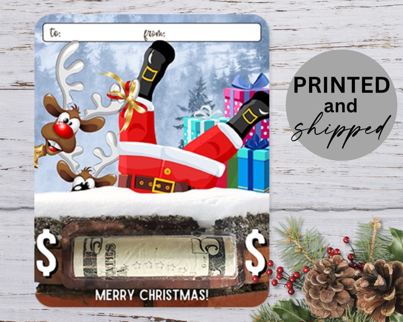 May include: A Christmas gift card with a cartoon image of Santa Claus falling on his back with reindeer peeking out from behind the snow. The card has a dollar sign on each side and the text "Merry Christmas!" at the bottom.