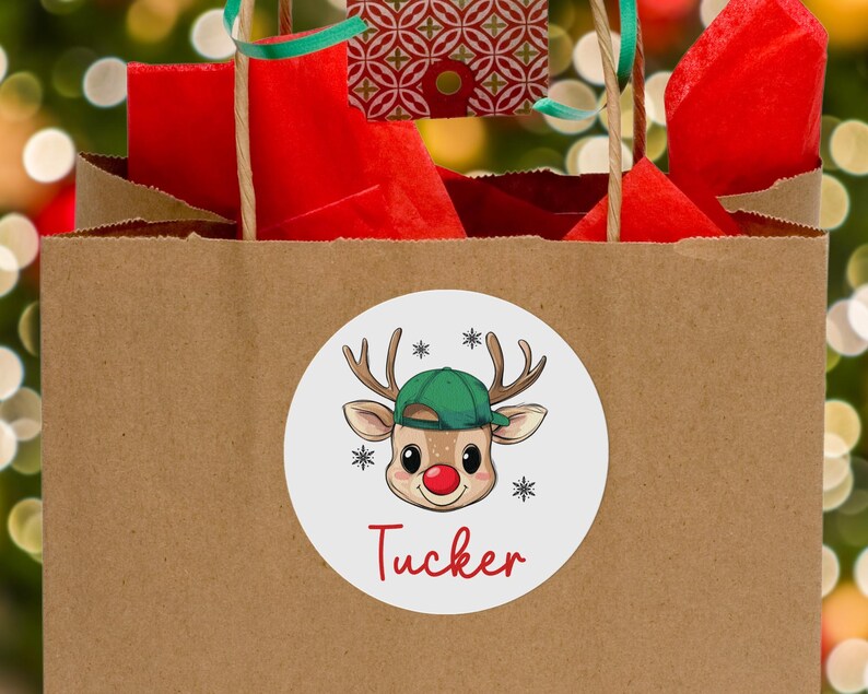 May include: A white round sticker with a cartoon reindeer wearing a green baseball cap. The reindeer has a red nose and is smiling. The sticker says "Tucker" in red letters.
