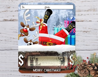 May include: A Christmas gift card with a cartoon image of Santa Claus falling down a chimney with two reindeer looking on. The card has a space to write "To:" and "From:" and a dollar sign with a space to write in an amount. The card says "Merry Christmas!" at the bottom.