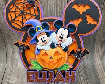 Puede incluir: Un adorno para pastel de Mickey Mouse y Minnie Mouse con temática de Halloween con una calabaza, murciélagos y una telaraña. El adorno está personalizado con el nombre "ELIJAH".