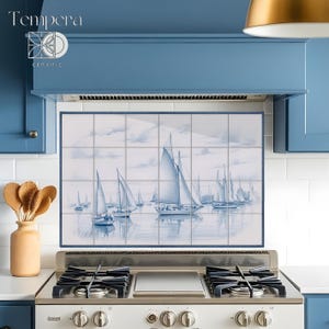 Puede incluir: Un salpicadero de azulejos de cerámica azul y blanco con un tema náutico. El salpicadero presenta una pintura de acuarela de veleros en el agua. El salpicadero está instalado sobre una estufa de acero inoxidable.