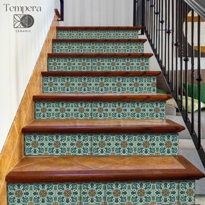 Könnte beinhalten: Treppe mit dekorativen Keramikfliesen mit einem sich wiederholenden Blumenmuster in Grün, Blau und Gelb. Die Fliesen sind auf Holzstufen mit dunkler brauner Umrandung verlegt. Der Markenname "Tempera Ceramic" ist sichtbar.